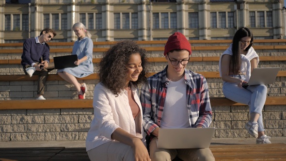 Students doing projects on laptops outside the university alt
