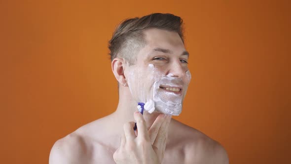A Young Caucasian Man with Shaving Foam on His Face Performing a Morning Routine