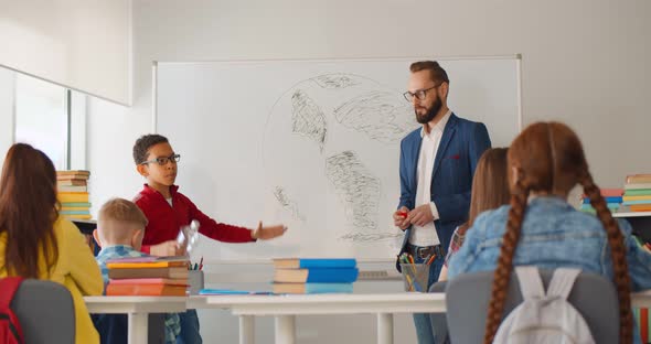 Cheerful Teenage Students Sitting in Classroom and Discussing Ecological Problems alt