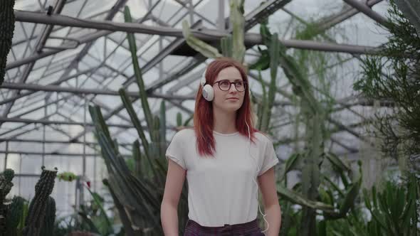 Modern Girl in a Greenhouse, Listens To Music and Enjoys Plants