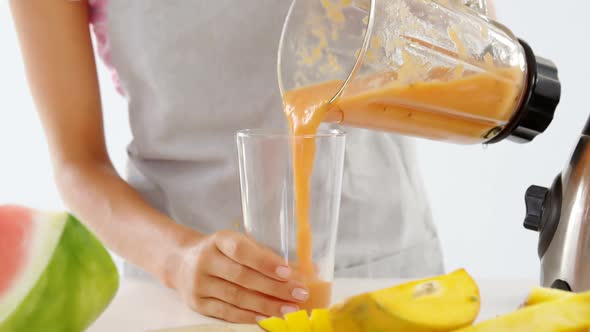 Mid-section of woman pouring smoothie in glass alt
