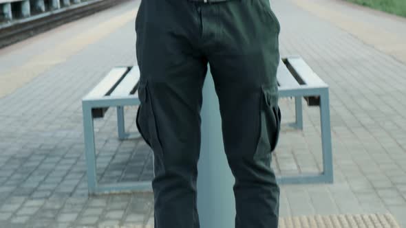 Man in Gas Mask in Jacket with Hood and Backpack Standing on Railroad Platform
