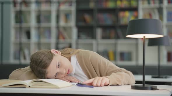 School girl at boring lesson playing with pen alt