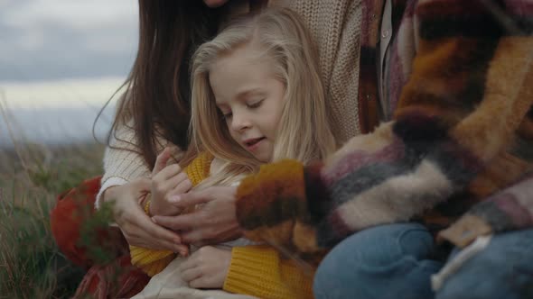 Pretty Female Child Playing in Grass with Her Two Mothers alt