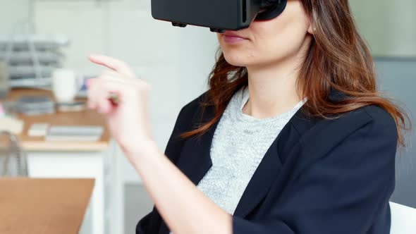 Female executive using virtual reality headset alt