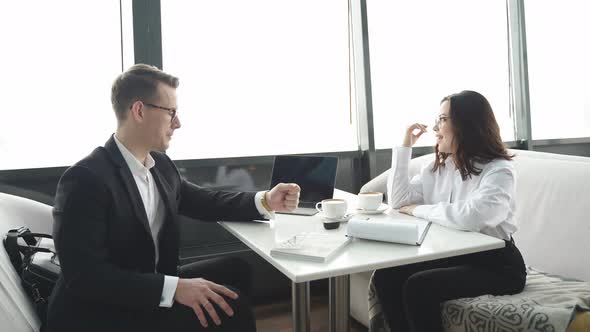 Business Partners Man and Woman in Formal Wear Sit Talking Discussing in Restaurant