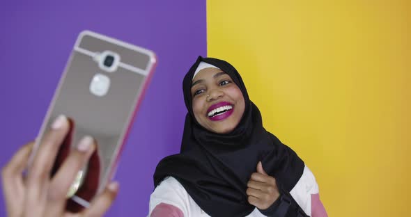 Portrait of Smiling African Black Muslim Girl Posing at Color Studio Background Taking Selfie Photo alt