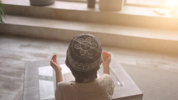 Muslim little boy reading the Koran in prayer hat and arabic clothes with rosary beads