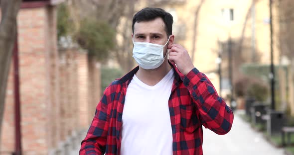 Young man take off medical mask and smiling looking at the camera.
