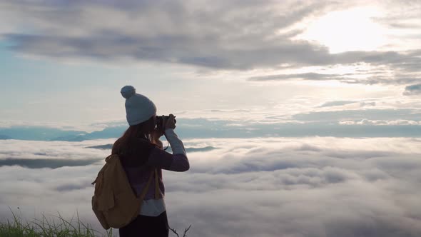 Young woman traveler taking a beautiful sunrise and the sea of mist on the mountain