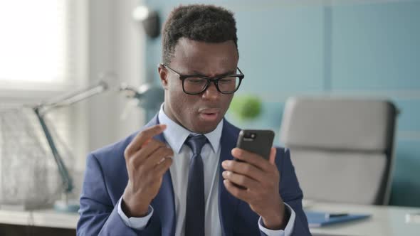 Portrait of African Man Reacting to Loss on Smartphone alt