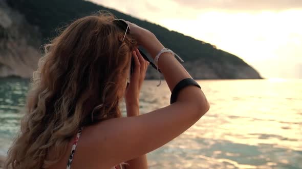 Woman Taking Pictures at Sunset on the Beach near the Sea on Vacation.