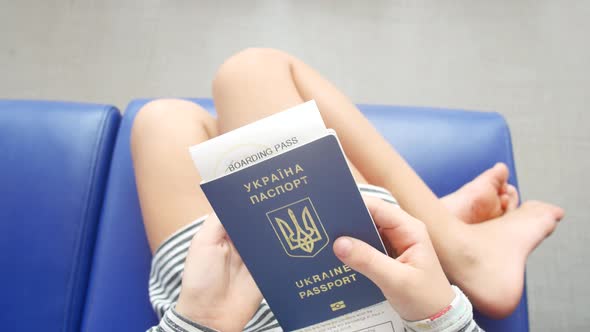 Sad Ukrainian Child Refugee at the Airport with a Passport in His Hands alt