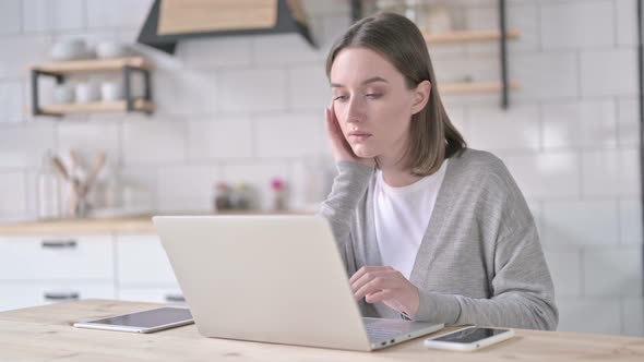 Young Woman Thinking and Working on Laptop alt