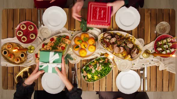 Friends Giving Presents to Each Other Top View Celebrating New Year Sitting at Dining Table alt
