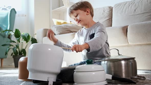 Child Drummer Having Fun Drum Playing on Kitchen Pans at Home alt