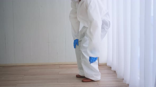 Woman staff with PPE suit sit on the floor and take off hygiene mask look tire or exhaust