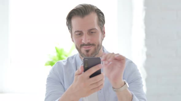 Young Man Celebrating Success on Smartphone alt