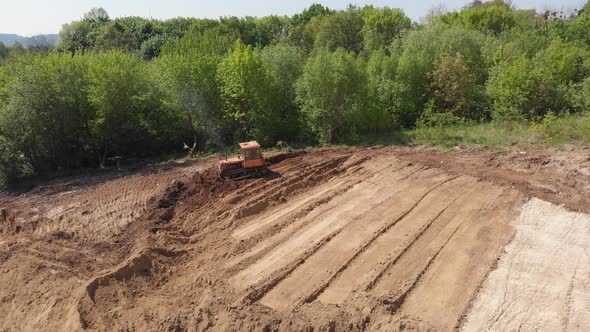 Aerial view of bulldozer flattening hill surface on further construction site