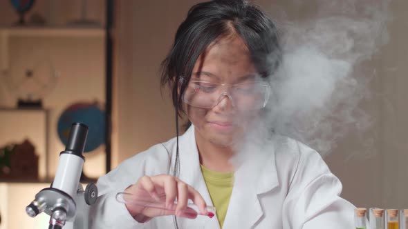 Young Asian Scientist Girl With Dirty Face Mixing Chemical Liquids In Flasks alt