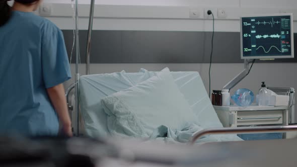 Woman Working As Nurse Preparing Bed in Hospital Ward alt