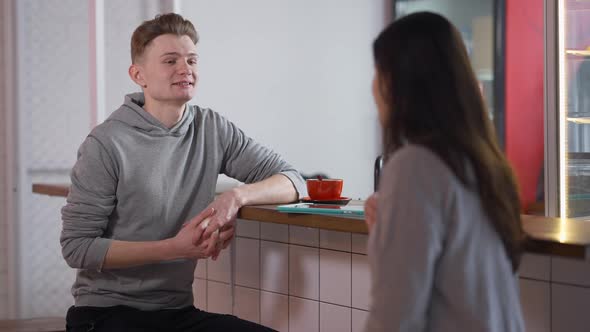 Young Positive Caucasian Boyfriend Talking with Girlfriend in Student Canteen Sitting at Counter alt