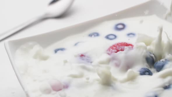 Plate with fresh strawberries and blueberries, pour over white milk, slow motion. alt