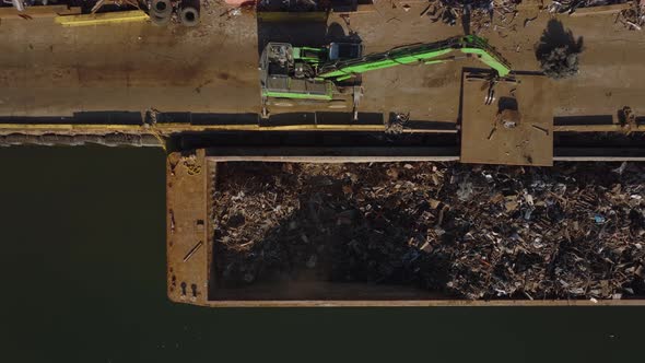 Aerial Birds Eye Overhead Top Down Ascending Shot of Loader Moving Metal Scrap to Barge alt