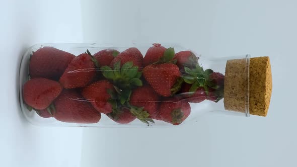 Vertical orientation video: Strawberries rotating on a white background. Strawberry ripe season