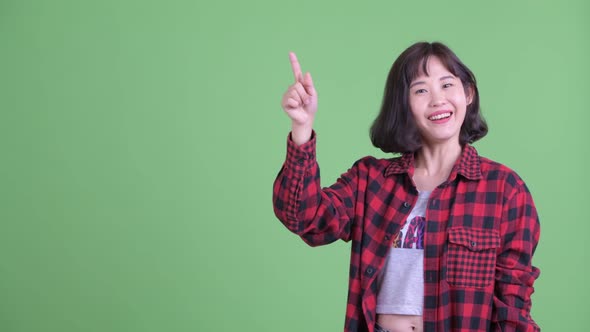 Happy Asian Hipster Woman Thinking While Pointing Up alt