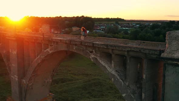 Female Sports Tourist Is Walking Over an Ancient Bridge at Sunset alt