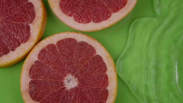 Crystal Clear Water Flowing Slow Mo on Grapefruit Slices on Light Green Backdrop