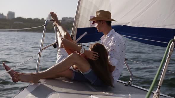 Young Romantic Couple is Sitting on the Yacht's Bow Embracing alt