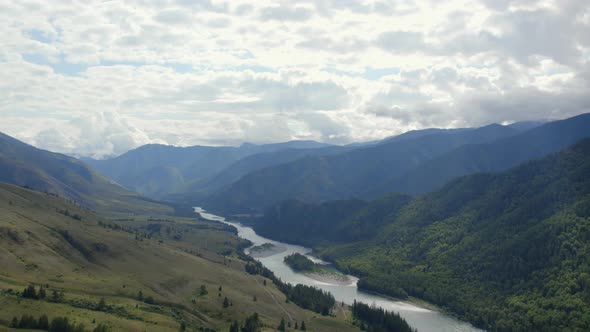River Katun between green mountains of Ak-Kem valley under white clouds and blue sky
