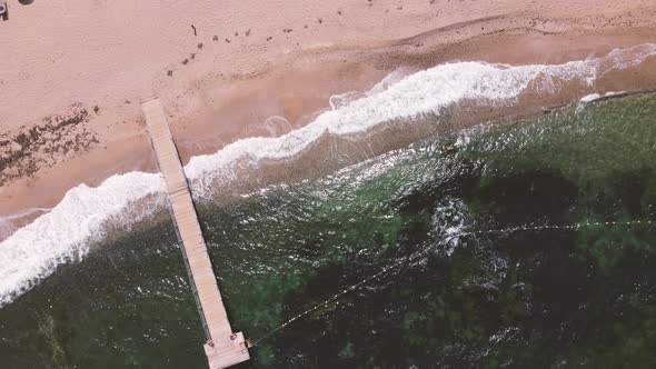 aerial shot above beach waves crashing alt