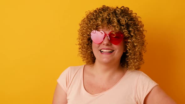 Cheerful 30s Woman with Afro Hairstyle Having Fun on Yellow Background