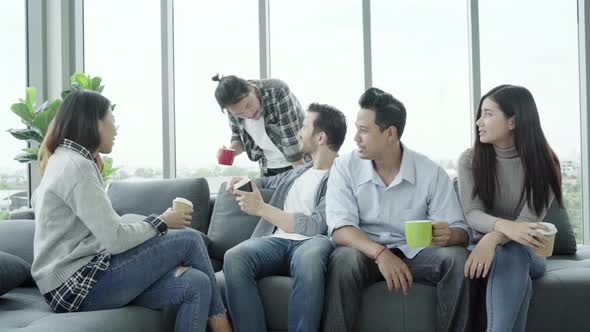 People group team holding coffee cups and discussing something with smile while sitting on couch alt