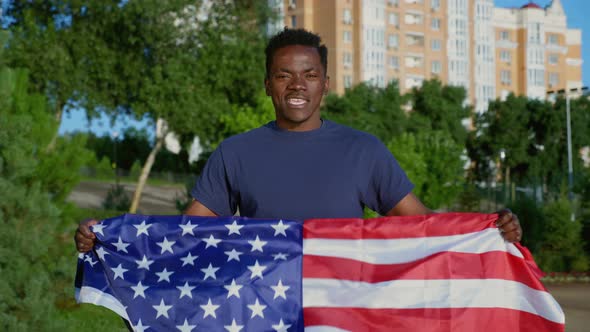 Portrait Smiling AfroAmerican Man Holding American Flag Looks Camera Says USA alt