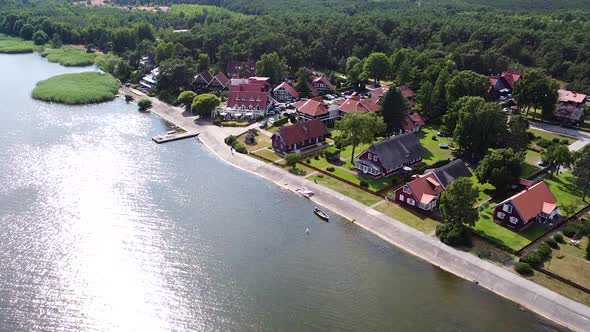 Colorful buildings of Pervalka with sun reflection in Curonian Lagoon, aerial view alt
