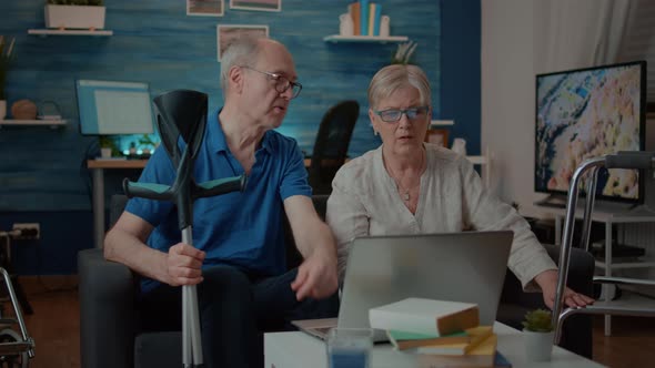 Old People with Disability Browsing Internet on Laptop alt