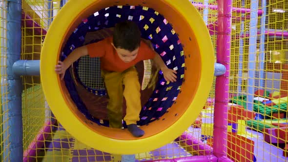 A Little Boy Runs Through a Tunnel in the Playroom