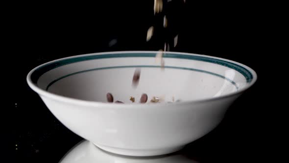 Filling cereals in a white bowl with a green circle on it in slow motion. alt