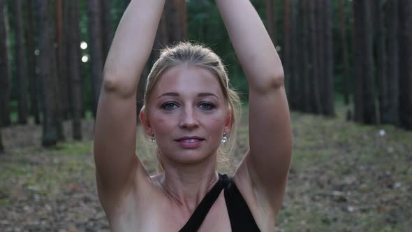 Young Fit Woman Making Namaste Gesture in Lotus Pose Closing Eyes at Forest