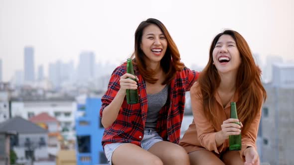 Young Asian woman lesbian couple clinking bottles of beer party on the rooftop. alt