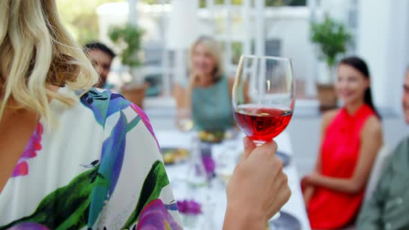 Friends applauding woman while having glass of wine alt