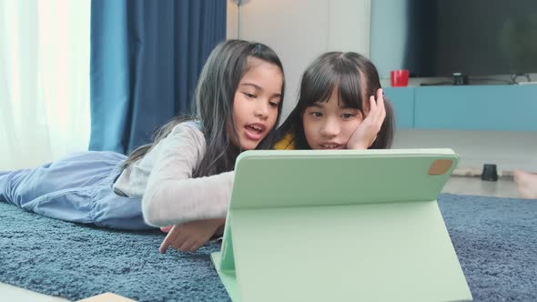 young asian daughter sibling child happiness lay down study online e-learning on floor