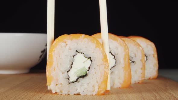 Human Hand Takes A Sushi From A Row By Chopsticks alt