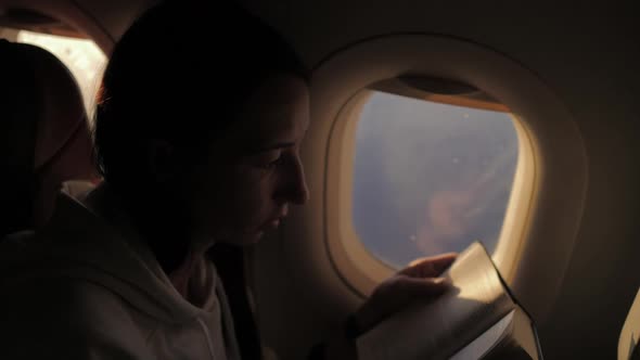Woman Reading Book Inside Airplane alt