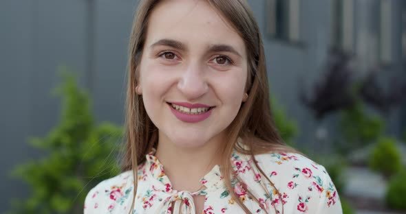 Young Pretty Woman in White Dress with Red Flowers Standing in Front of the Shopping Mall 