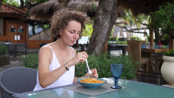 Caucasian Woman Takes Off Her Face Mask To Eat Pasta in Outdoor Restaurant alt